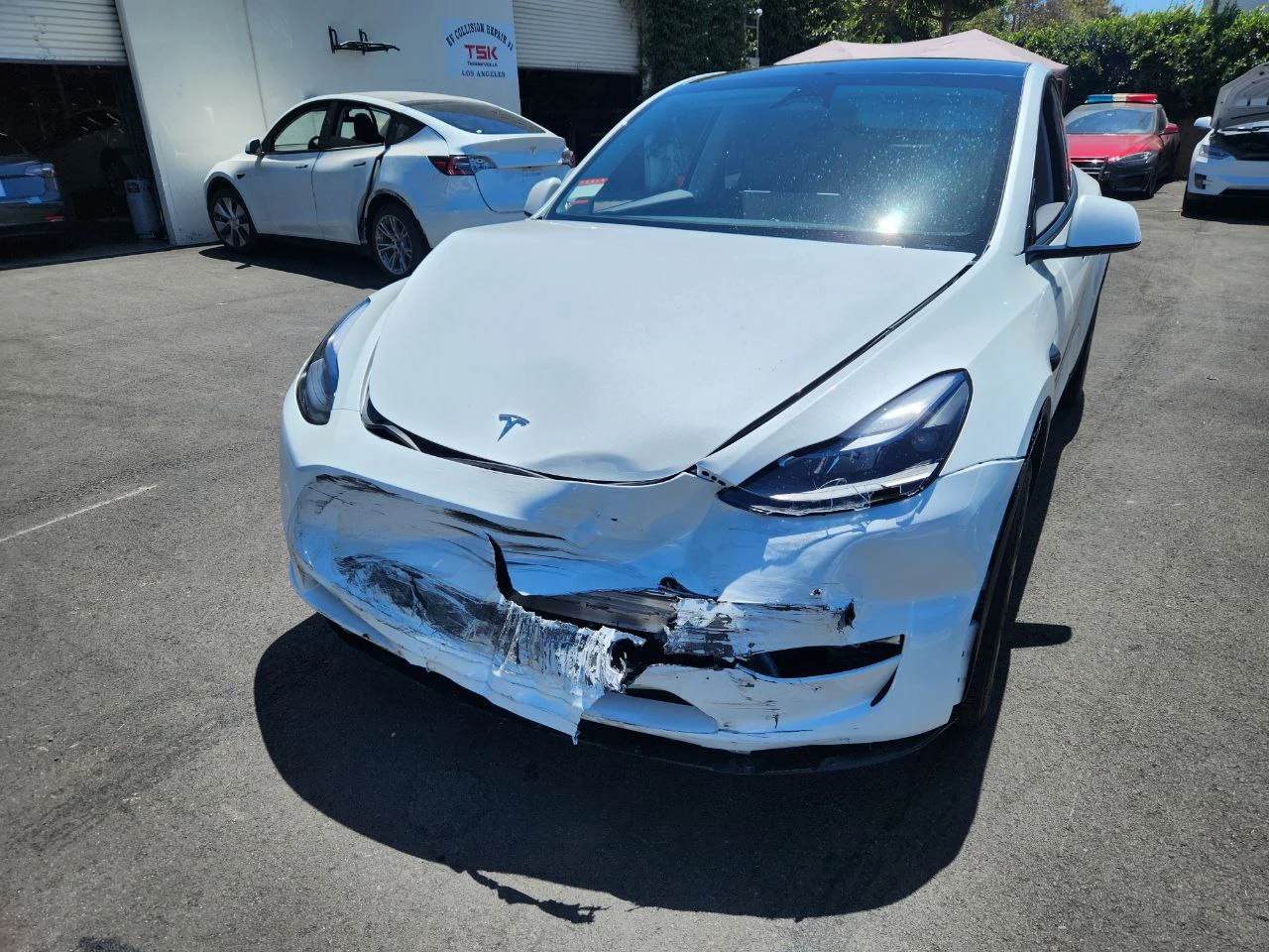 White Tesla Model Y with a crushed front bumper after a collision