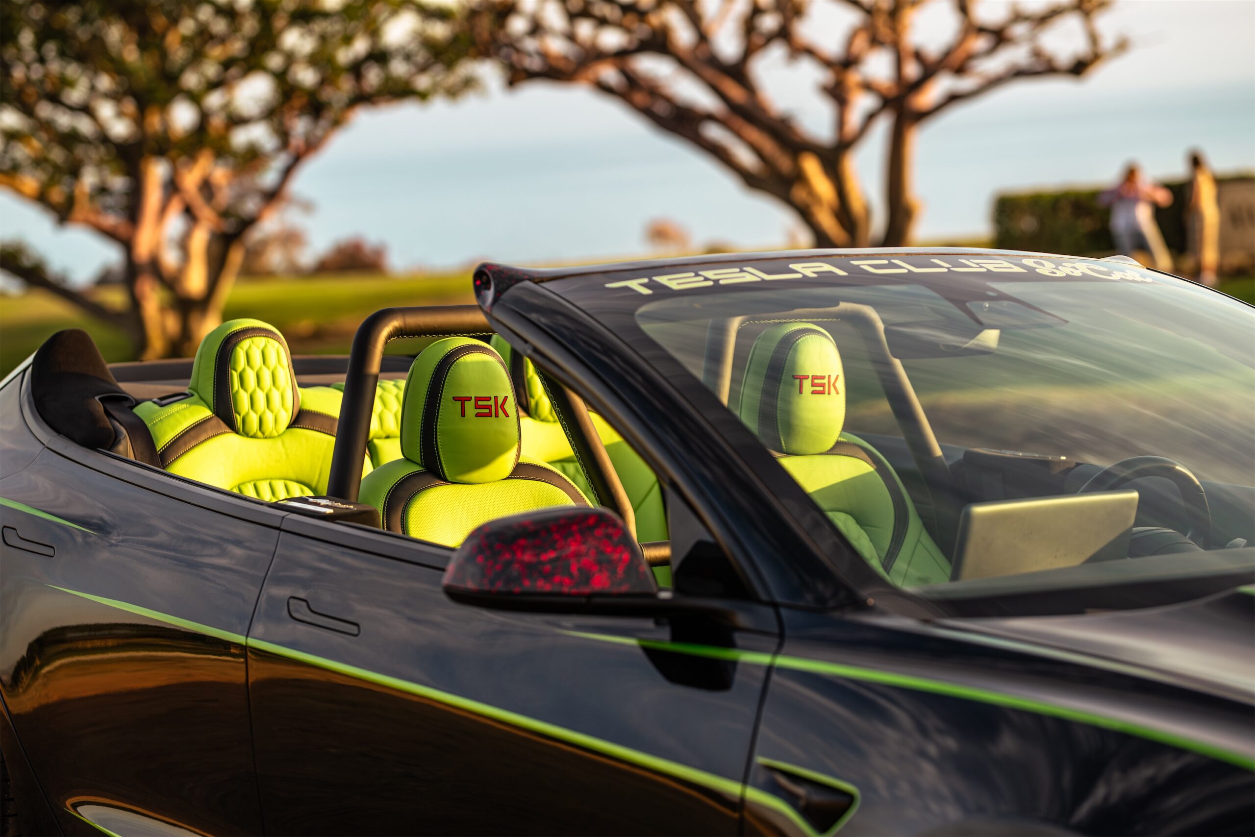 Roofless Tesla project: convertible Tesla with neon green TSK-branded seats and roll bar, parked outdoors