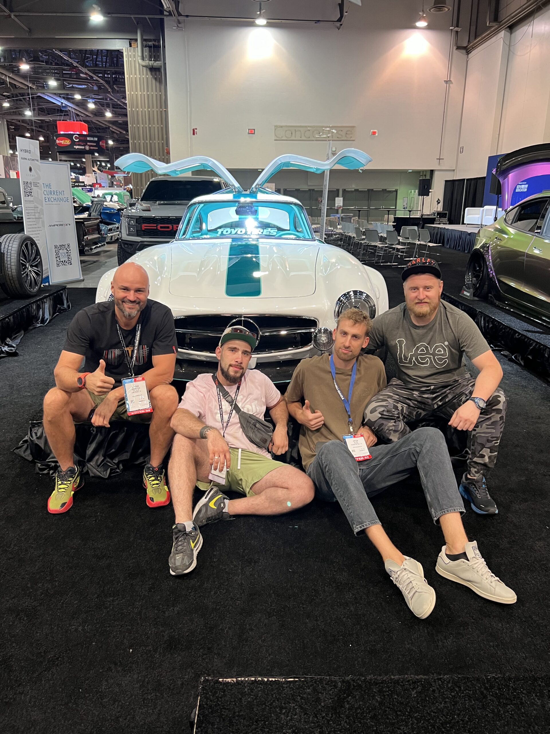 Tesla Gullwing project: four TSK team members seated in front of the car at a car show