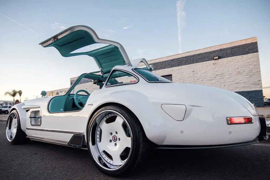 Tesla Gullwing project: white 300SL-style EV with gullwing doors open outside an industrial building