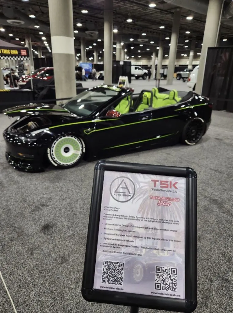 Roofless Tesla project: black Tesla Model 3 convertible with green stripes beside the TSK sign at the LA Auto Show