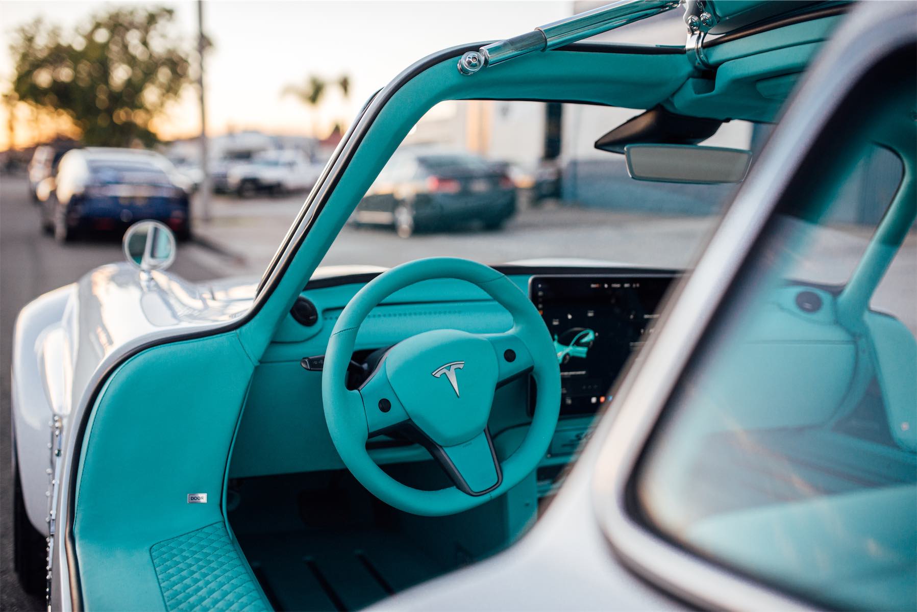 Tesla Gullwing project: turquoise Tesla steering wheel and touchscreen dashboard, gullwing door open