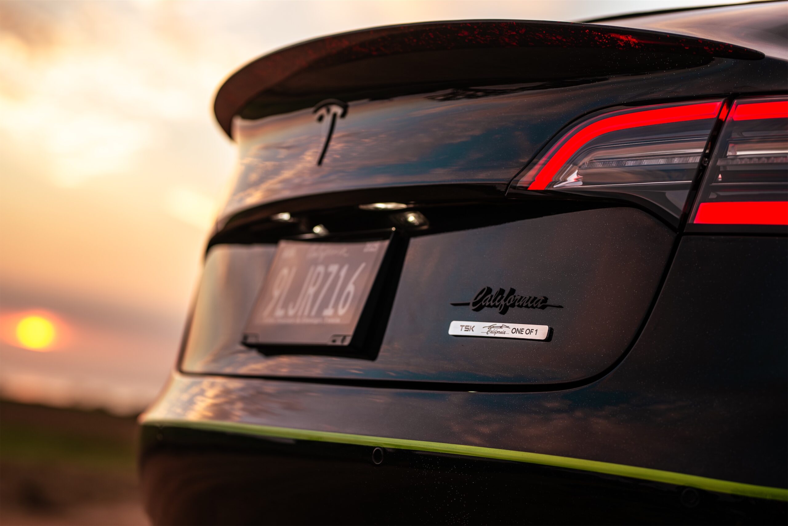 Roofless Tesla project: black Tesla Model 3 trunk, taillight and TSK One of 1 badge at sunset
