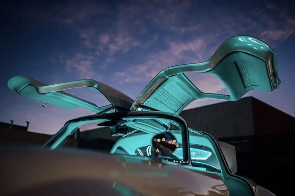 Tesla Gullwing project: gullwing doors with teal interior panels raised against a twilight sky