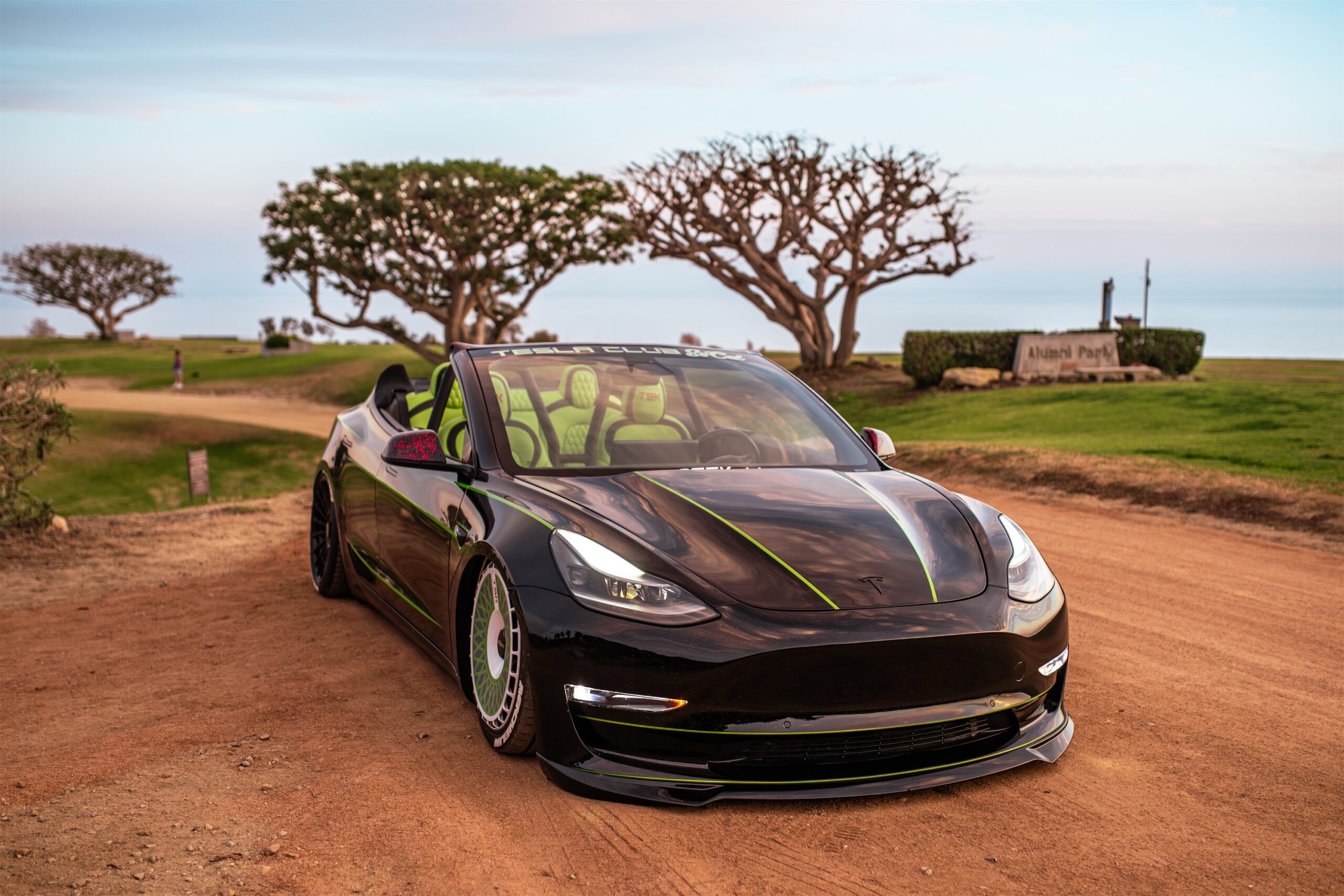 Roofless Tesla project: black Tesla Model 3 convertible with green stripes and interior on a dirt road