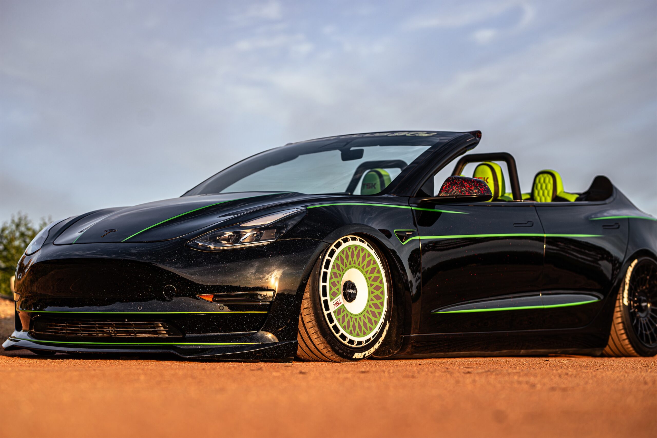 Roofless Tesla project: black Tesla Model 3 convertible with green stripes on desert dirt