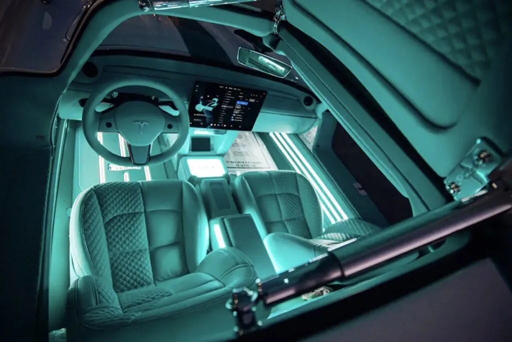 Tesla Gullwing project: quilted teal seats, the Model 3 steering wheel and screen seen through the open gullwing door