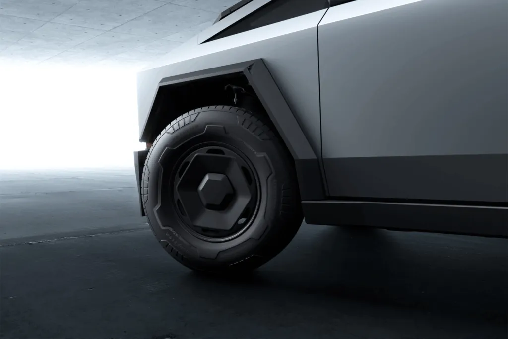 Close-up of a Tesla Cybertruck wheel, tire and stainless steel body panel