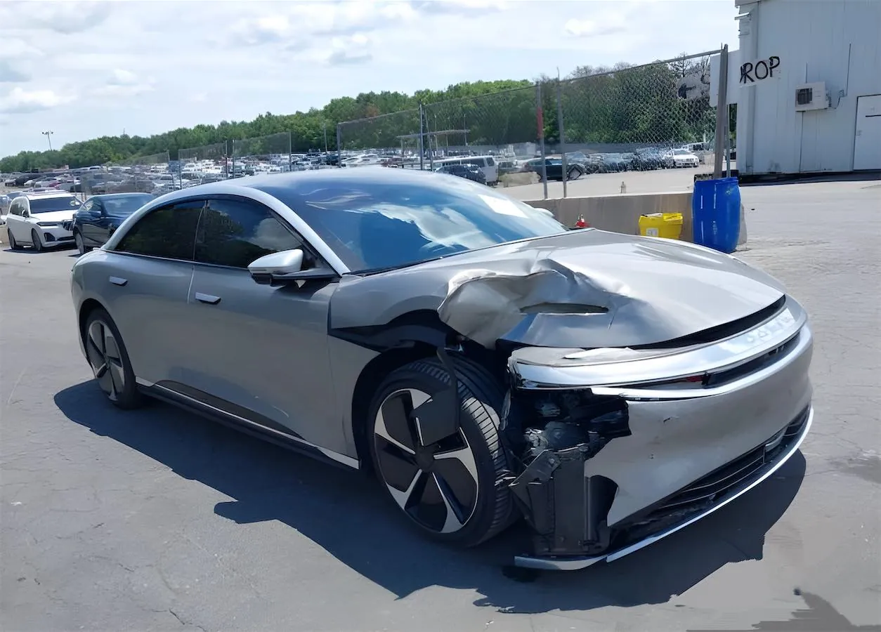 Silver Lucid Air sedan with heavy front-end collision damage in storage lot