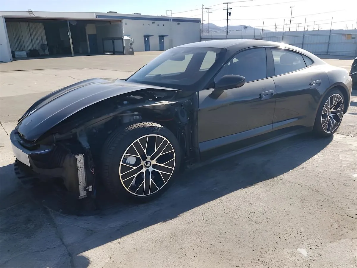 Black Porsche Taycan with front bumper removed, undergoing collision repair at TSK