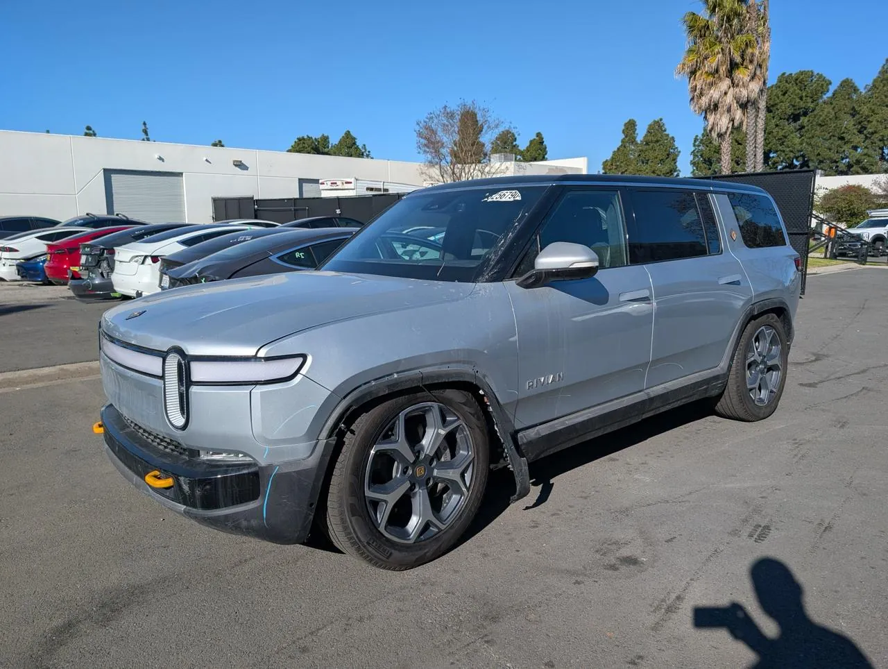 Silver Rivian SUV with front bumper damage parked at TSK collision repair lot