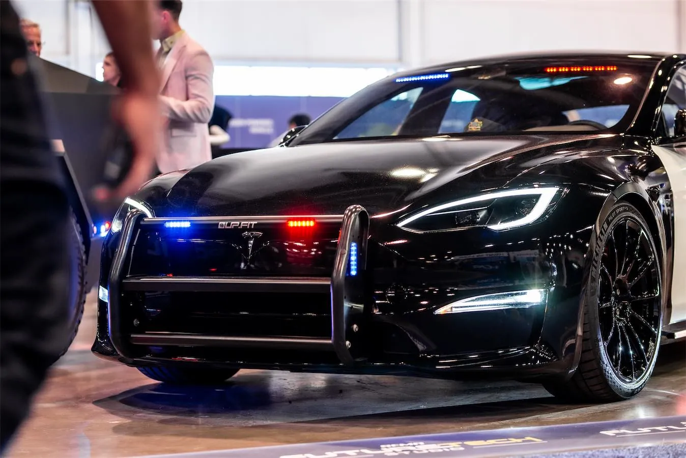 Police Interceptor project: black Tesla Model S with push bar and emergency lights at an auto show
