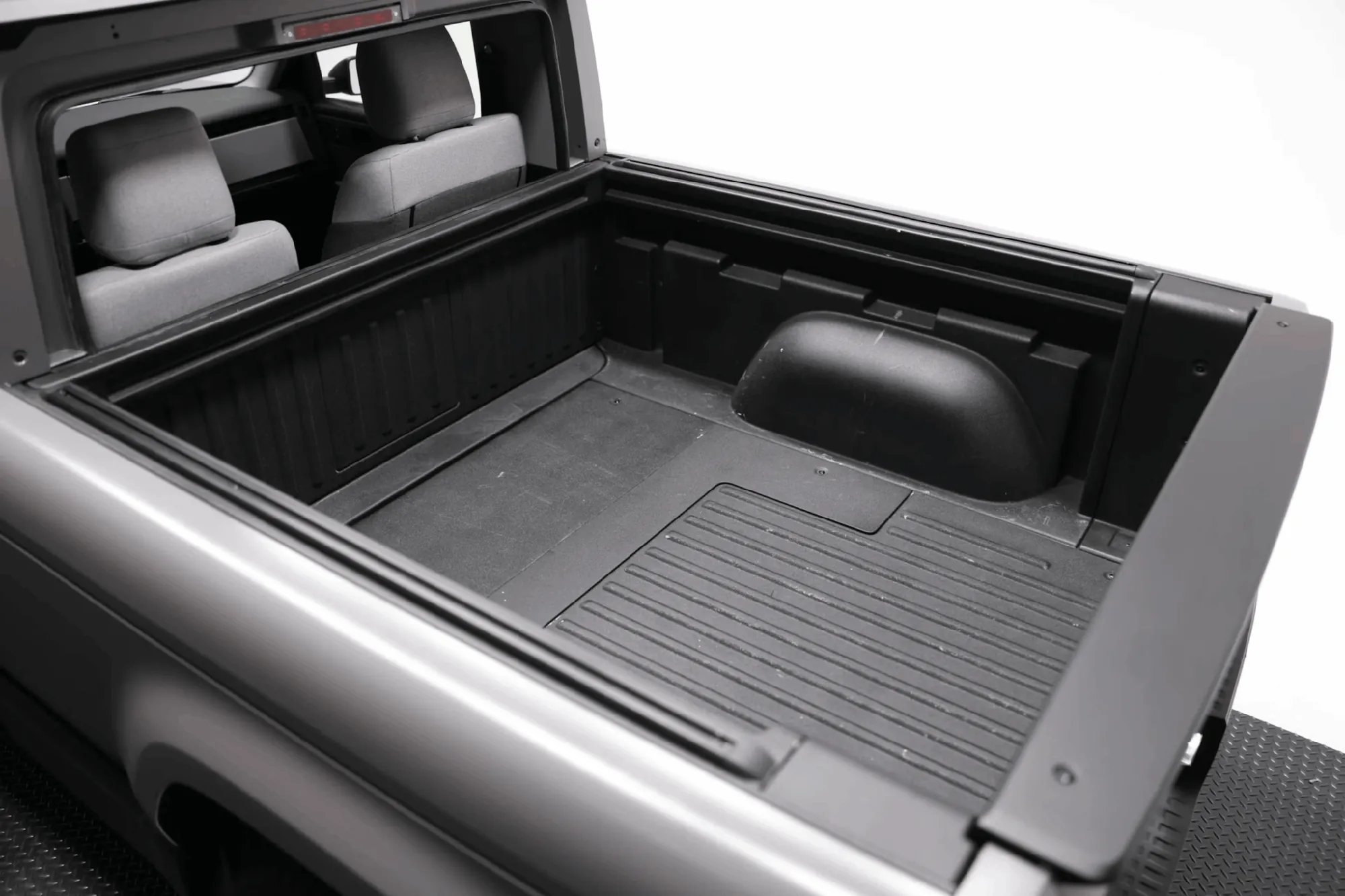 Slate electric pickup truck bed and rear seats viewed through open tailgate