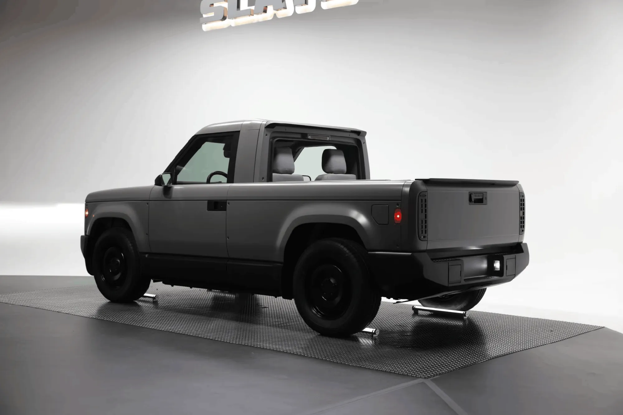 Slate electric pickup truck, gray, rear three-quarter view in studio showroom