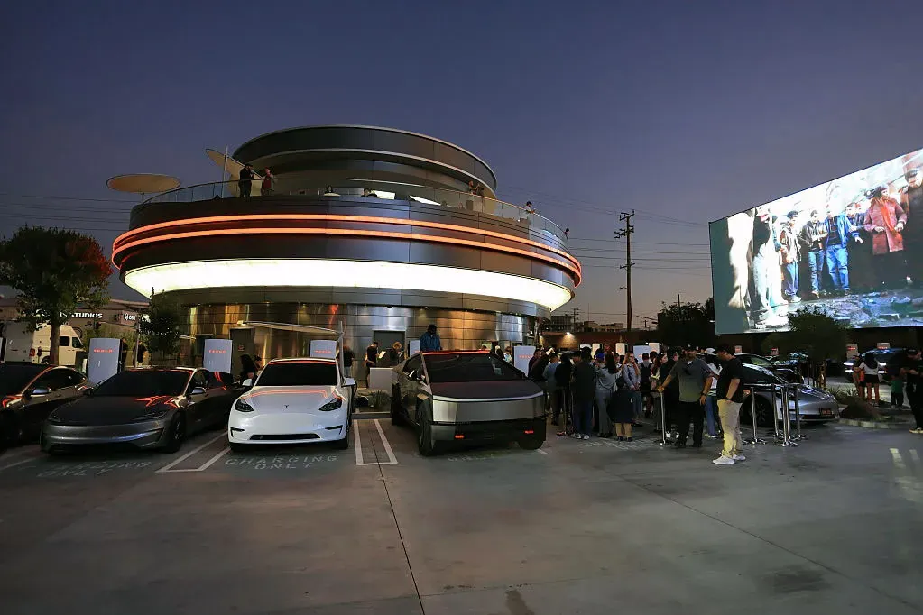 Tesla Diner at dusk with Cybertruck, Model 3 cars, and rooftop crowd outside