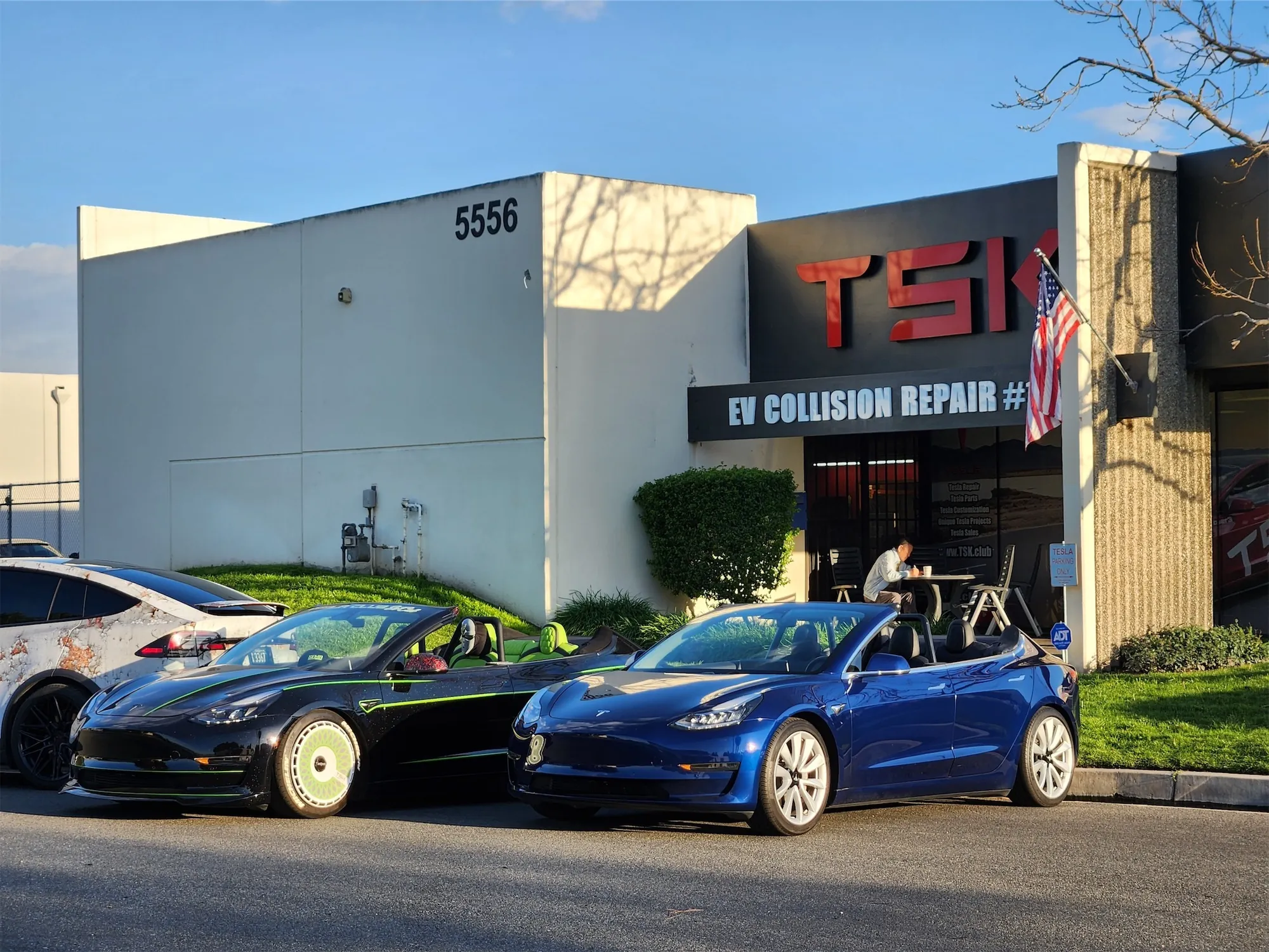 Two customized Tesla Model 3 convertibles parked outside TSK EV Collision Repair shop in Cypress