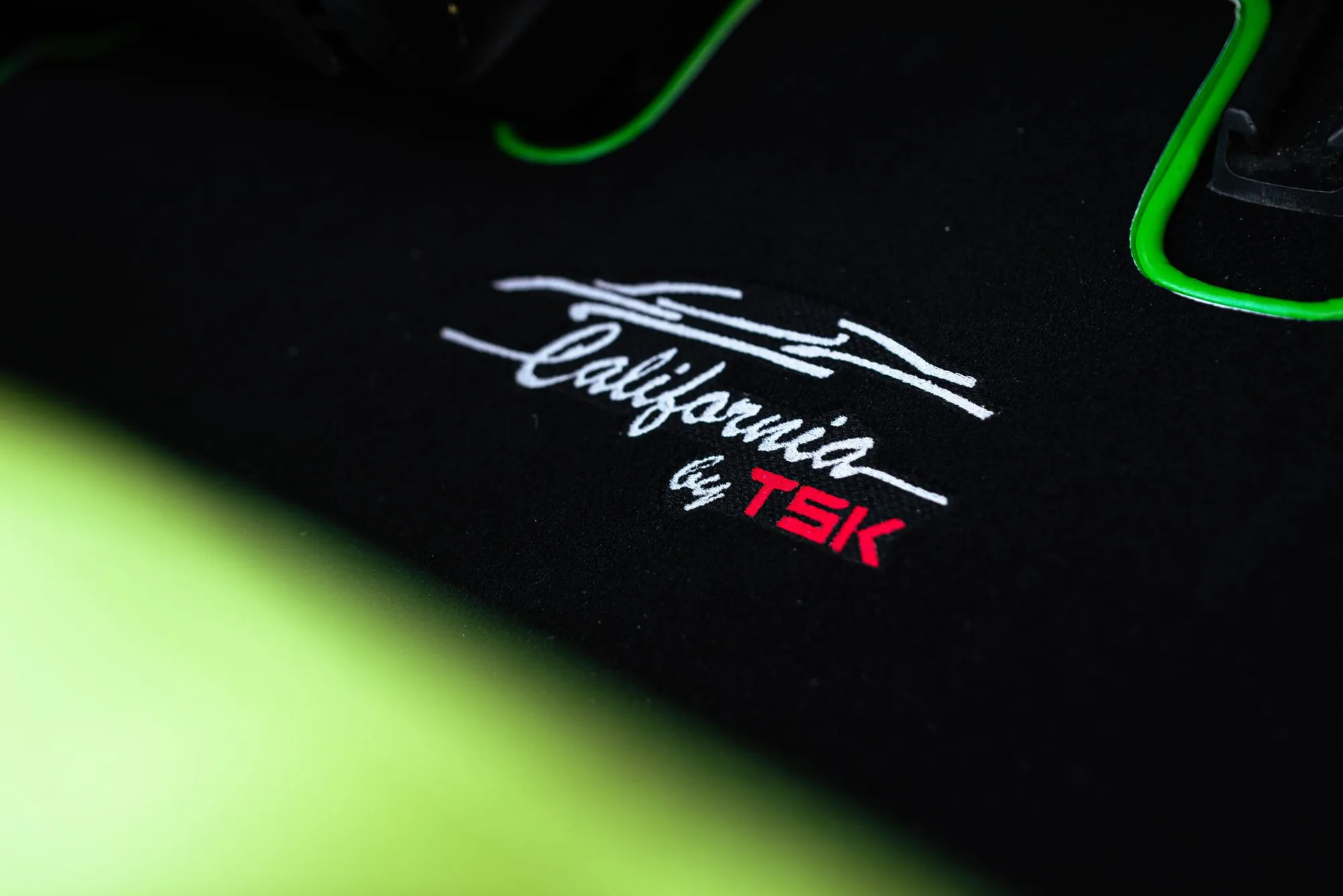 Roofless Tesla project: "California by TSK" embroidered logo on black fabric with green trim accents