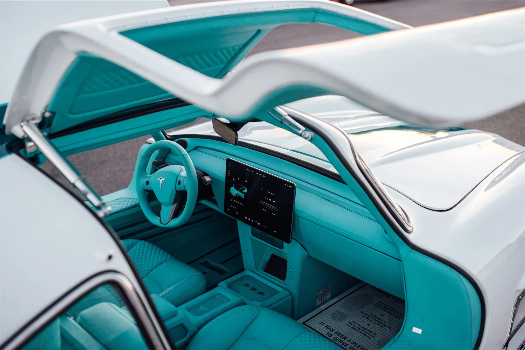 Tesla Gullwing project: teal leather interior and Tesla steering wheel under the open gullwing door