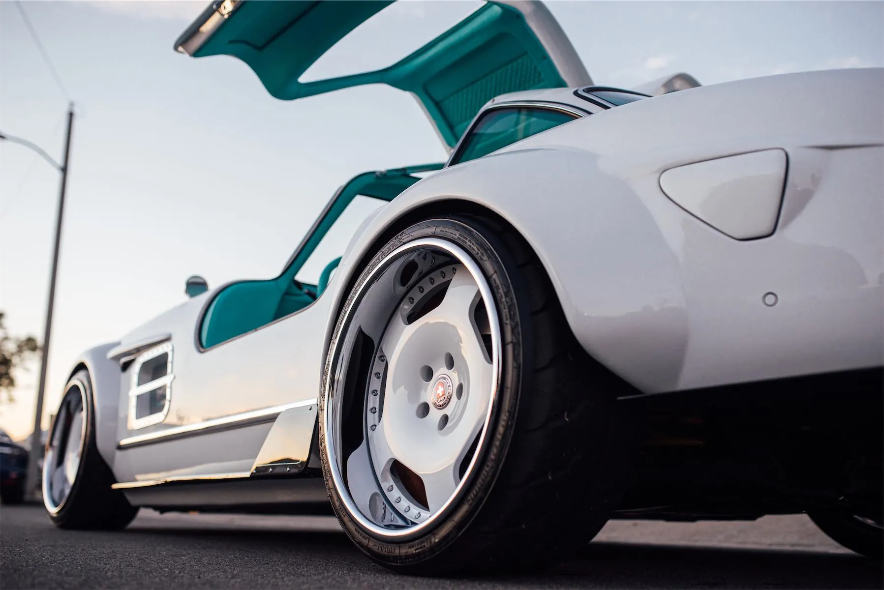 Tesla Gullwing project: teal gullwing door and polished wheel of the white EV