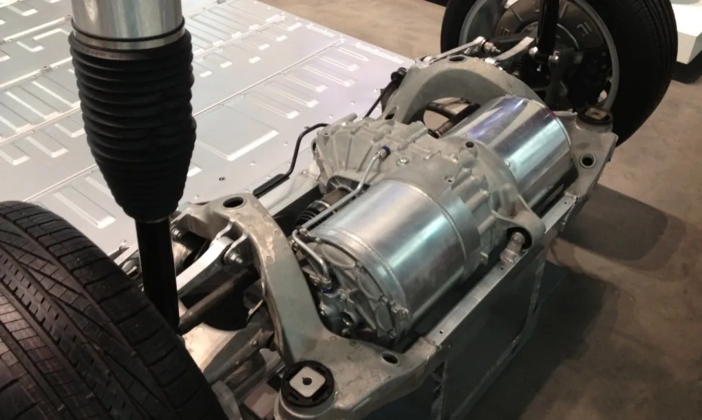 Tesla drive unit exposed on chassis with suspension components, Cypress service shop