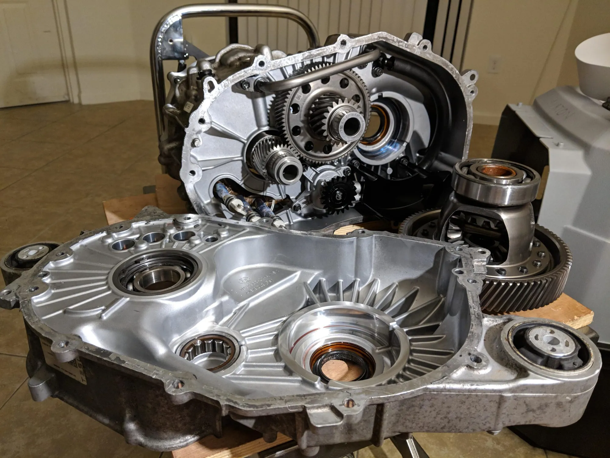 Disassembled Tesla drive unit showing gears, bearings, and differential housing during service