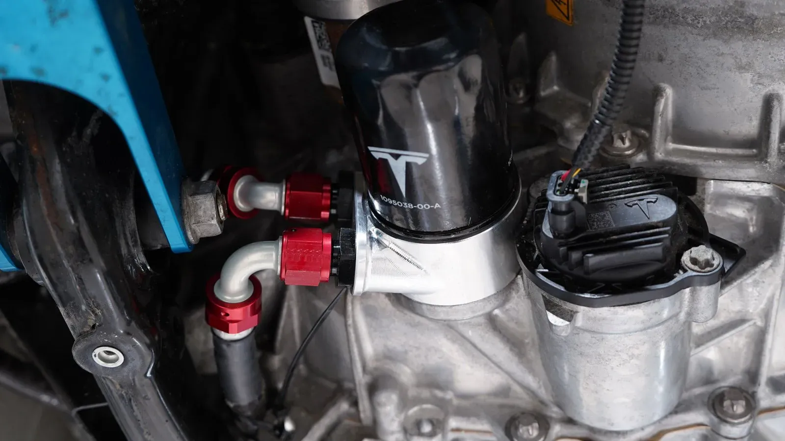 Tesla drive unit with oil filter and red braided fittings during service in Cypress