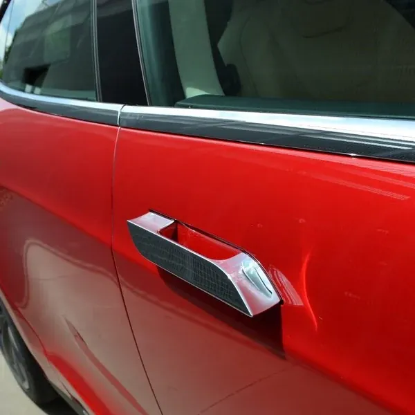 Red car door handle close-up showing flush handle design and body panel finish