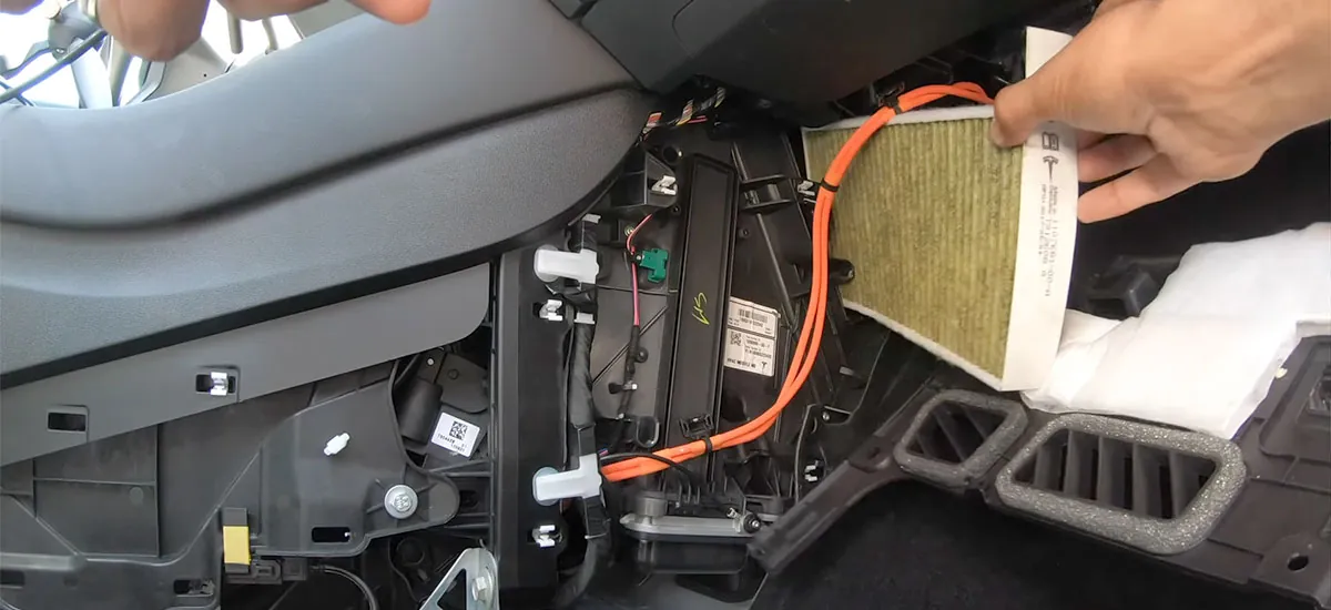 Technician removing cabin air filter during Tesla HVAC service at TSK