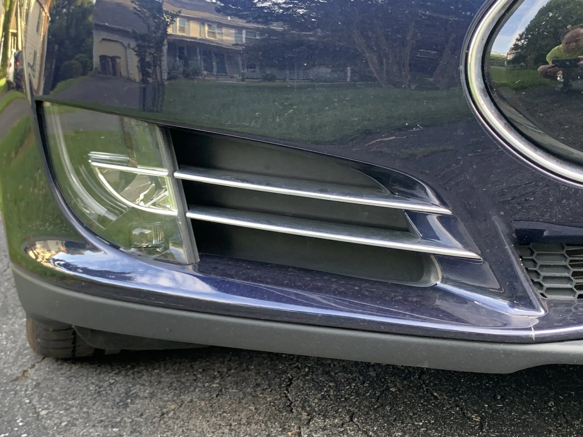 Close-up of dark blue car's front bumper vent and headlight during HVAC inspection
