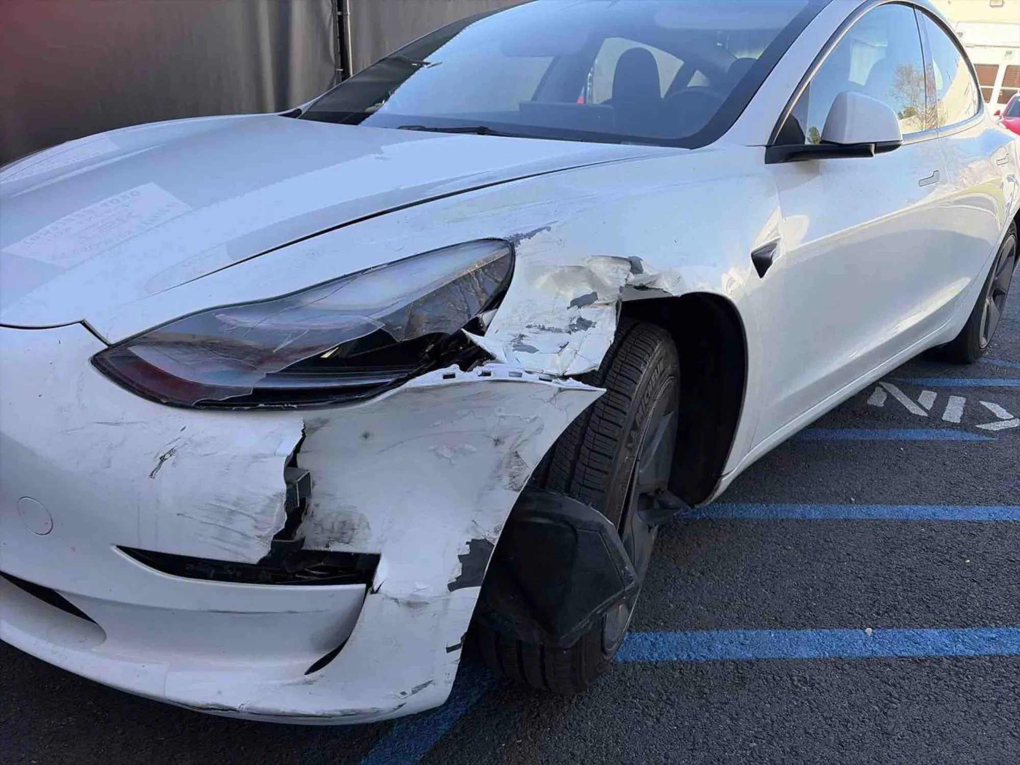 White Tesla Model 3 with crumpled front fender and headlight damage before repair in Irvine