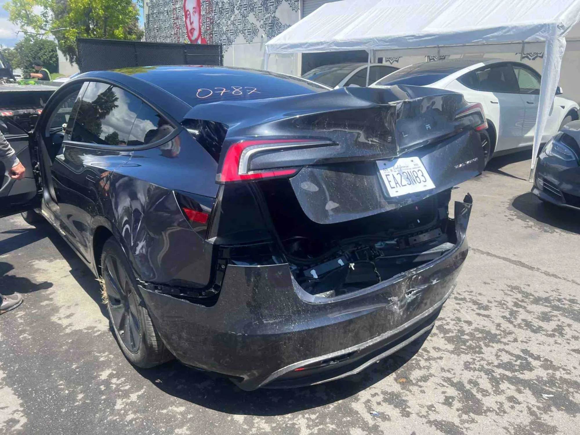 Black Tesla Model 3 with damaged rear bumper and trunk, awaiting collision repair in Irvine