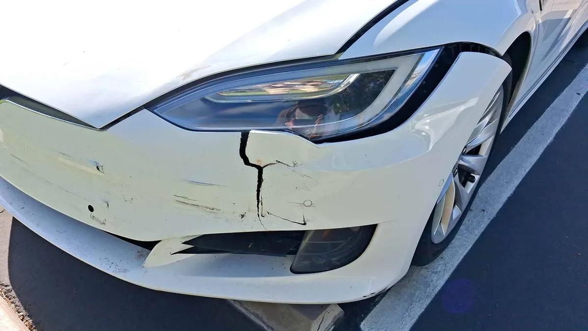 Cracked front bumper on white Tesla Model S before collision repair at TSK Irvine