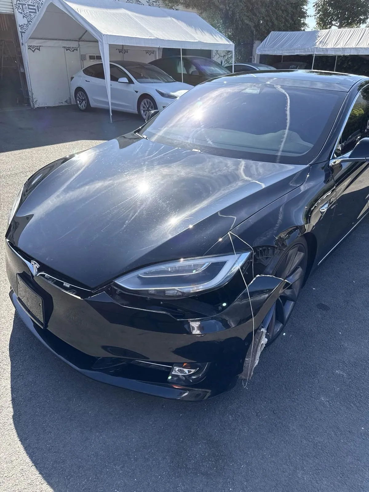 Black Tesla Model S with damaged front bumper before collision repair at TSK Irvine