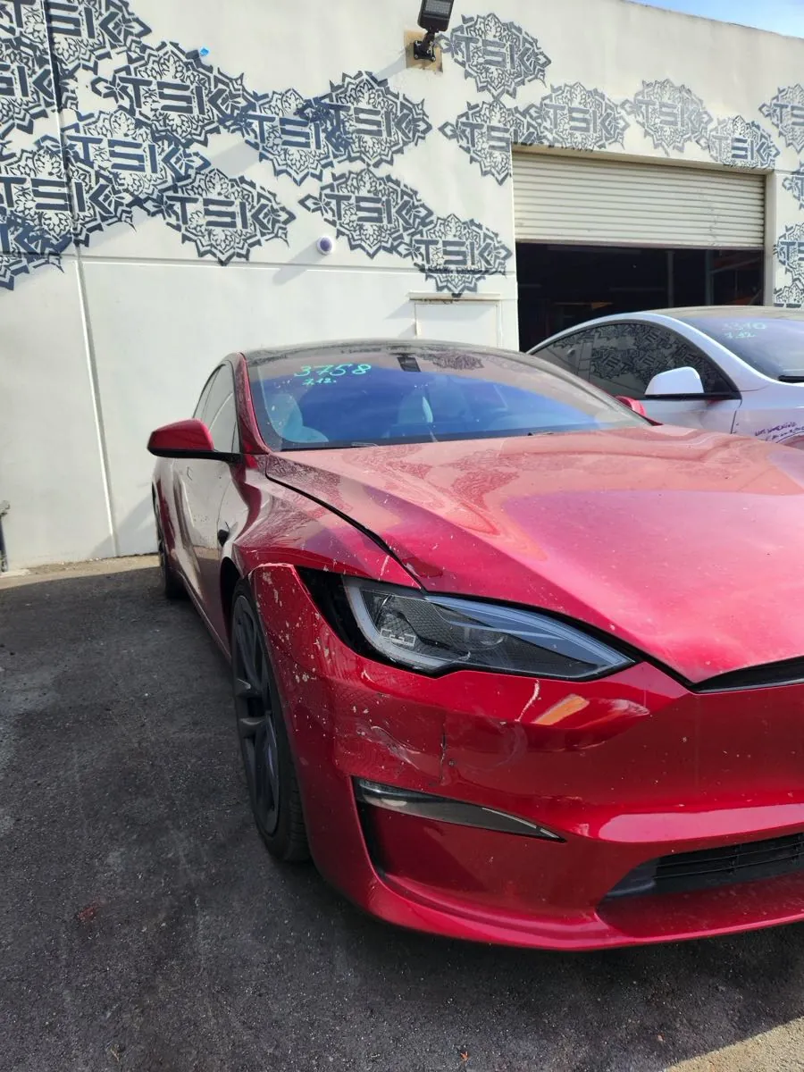 Red Tesla Model S with damaged front bumper at TSK Irvine collision repair shop