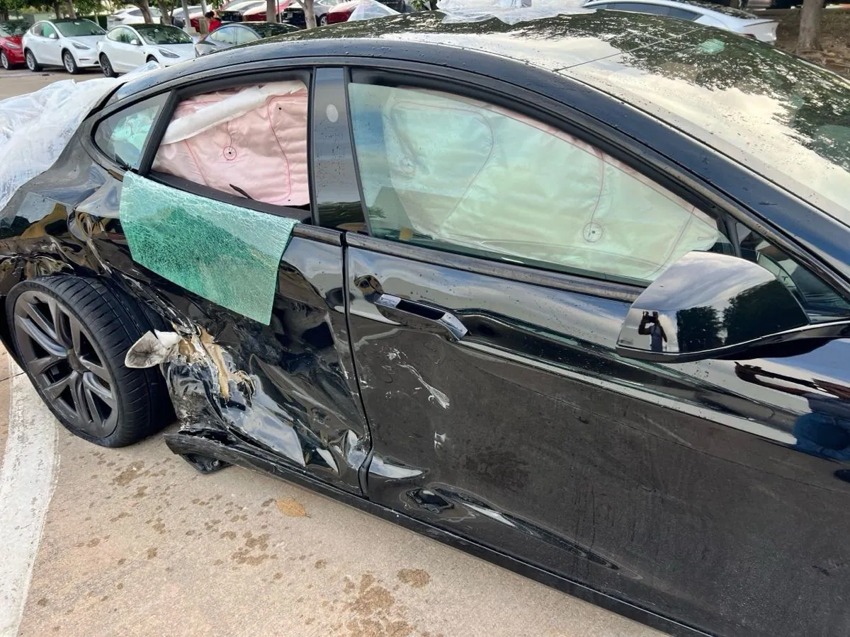 Black Tesla Model S with crushed front fender and shattered side window before repair
