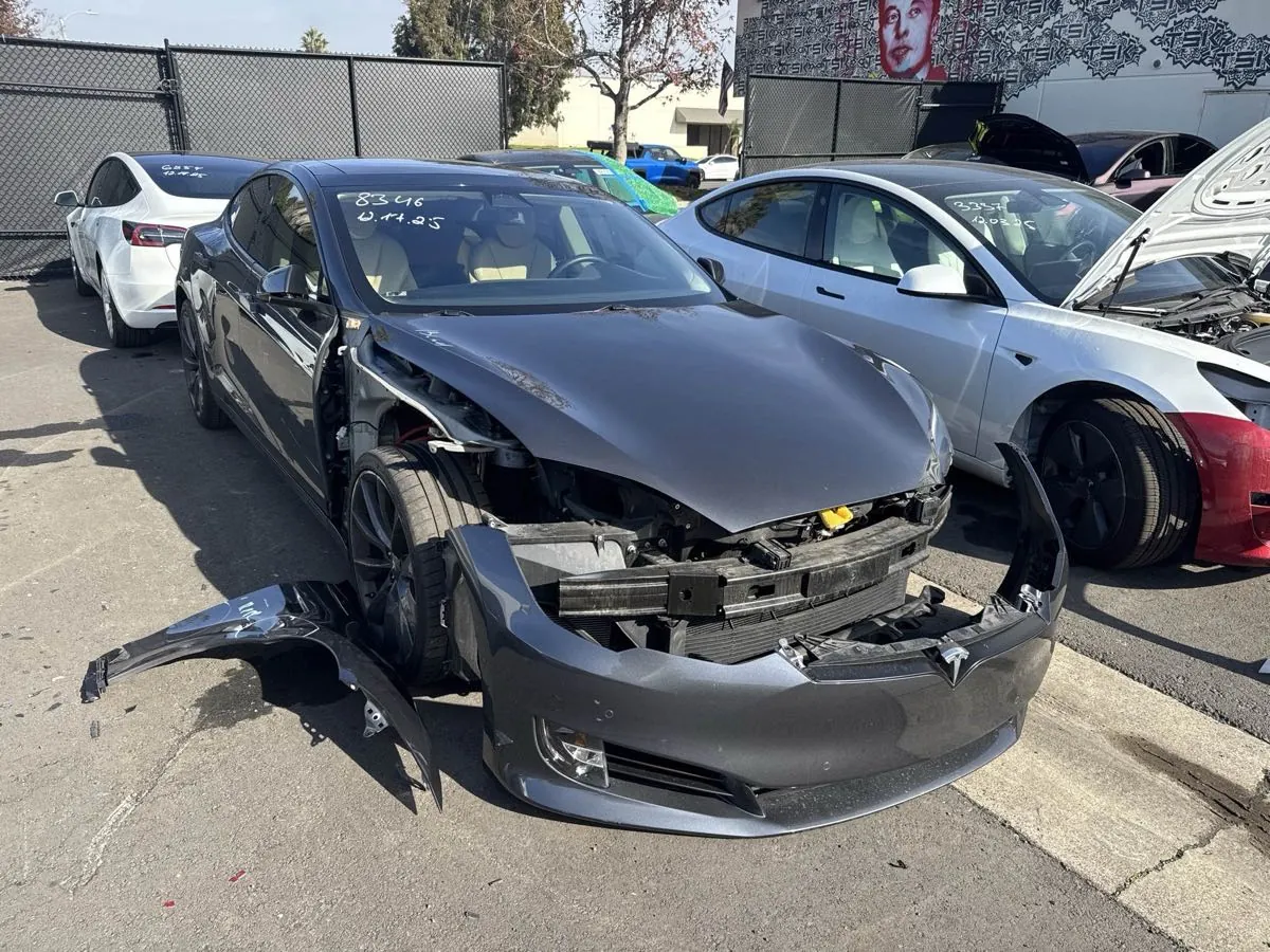 Gray Tesla Model S with front bumper and headlights removed for collision repair