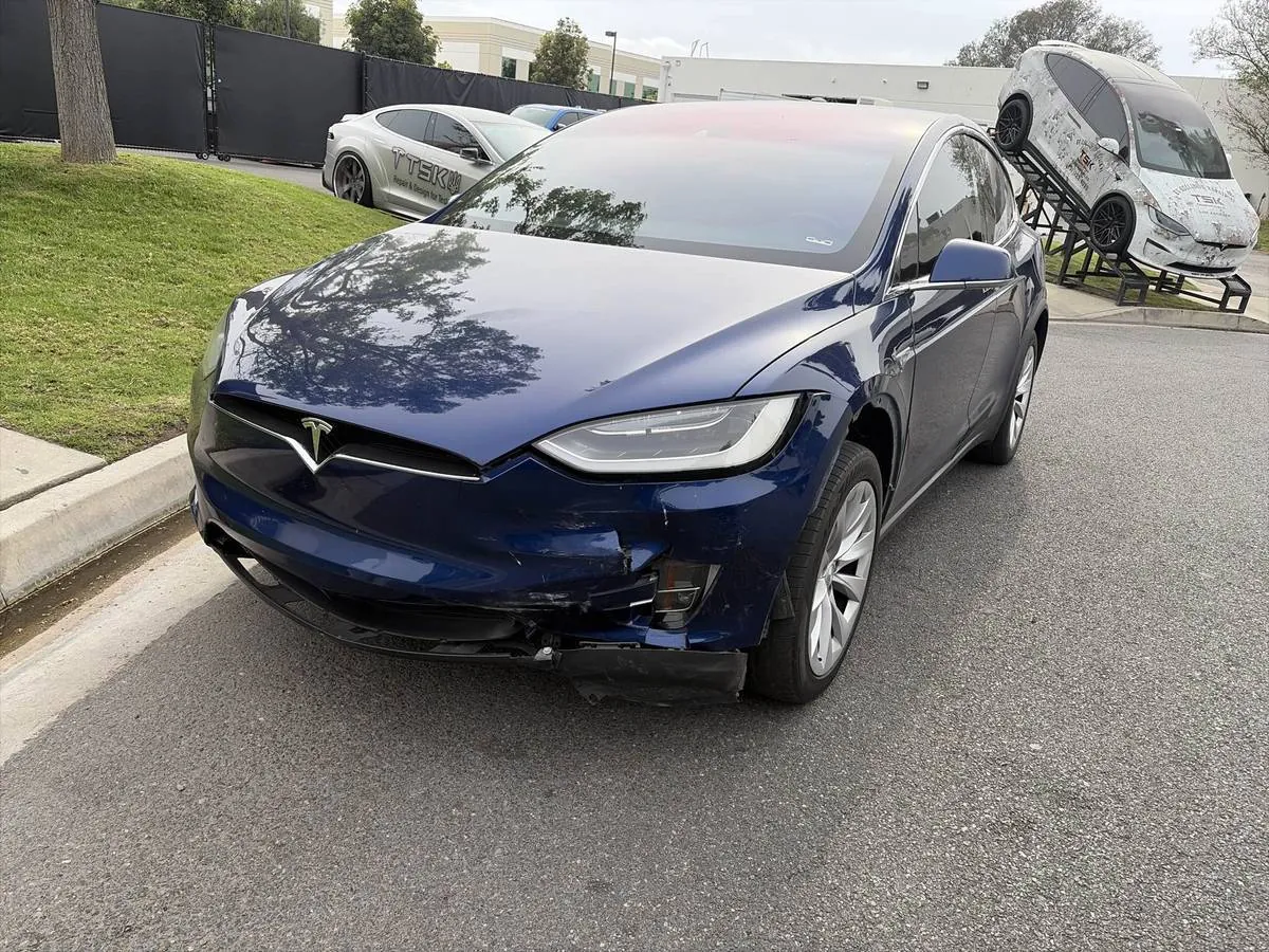 Blue Tesla Model X with damaged front bumper at TSK Irvine collision repair shop
