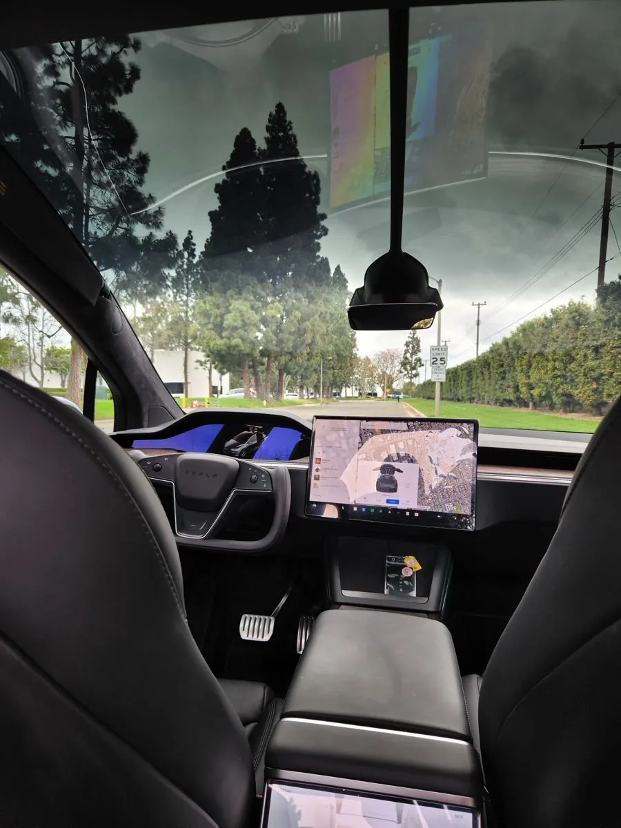 Tesla Model X interior view showing yoke steering wheel and center touchscreen display