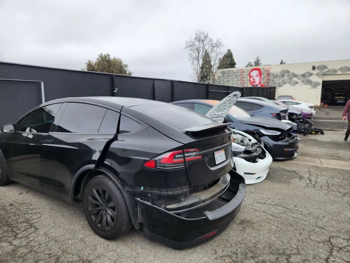 Damaged Tesla Model X with rear bumper detached, awaiting collision repair at TSK Irvine