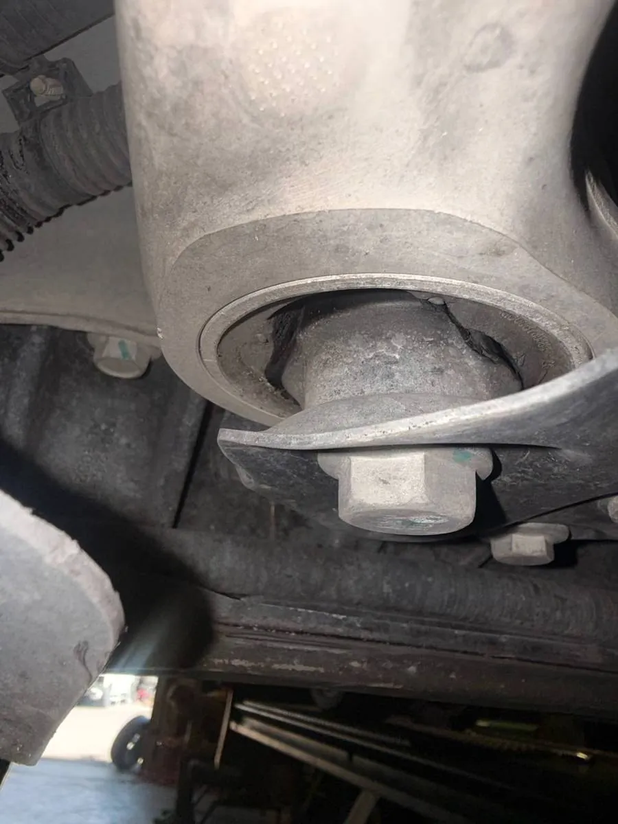 Close-up of Tesla Model X suspension bushing and bolt during undercarriage repair inspection