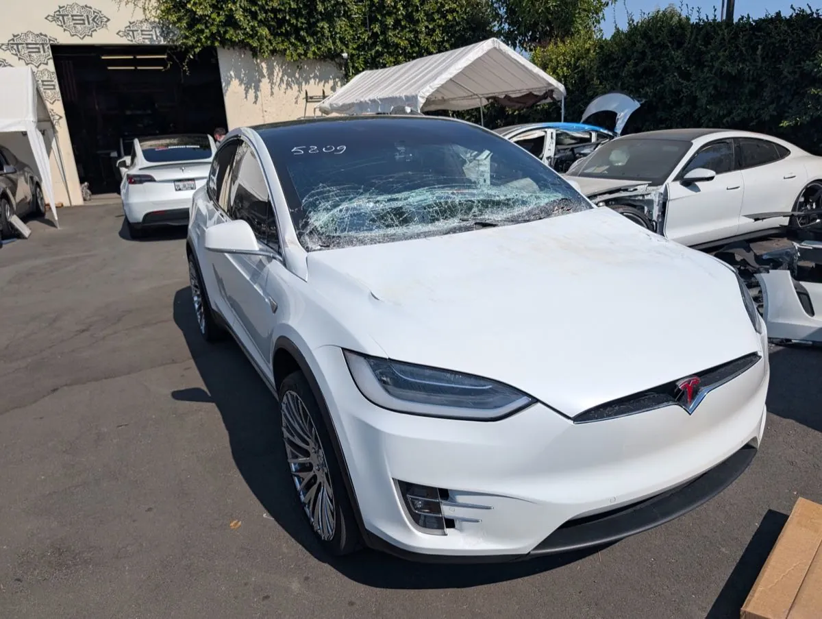White Tesla Model X with shattered windshield awaiting repair at TSK Irvine