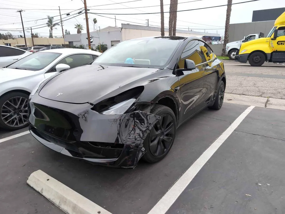 Black Tesla Model Y with damaged front bumper parked before repair at TSK Irvine