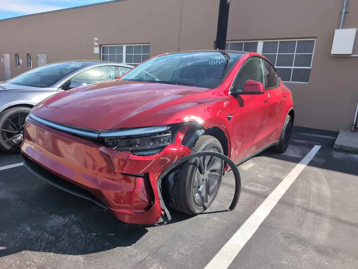 Red Tesla Model Y with front-end collision damage awaiting repair at TSK in Irvine