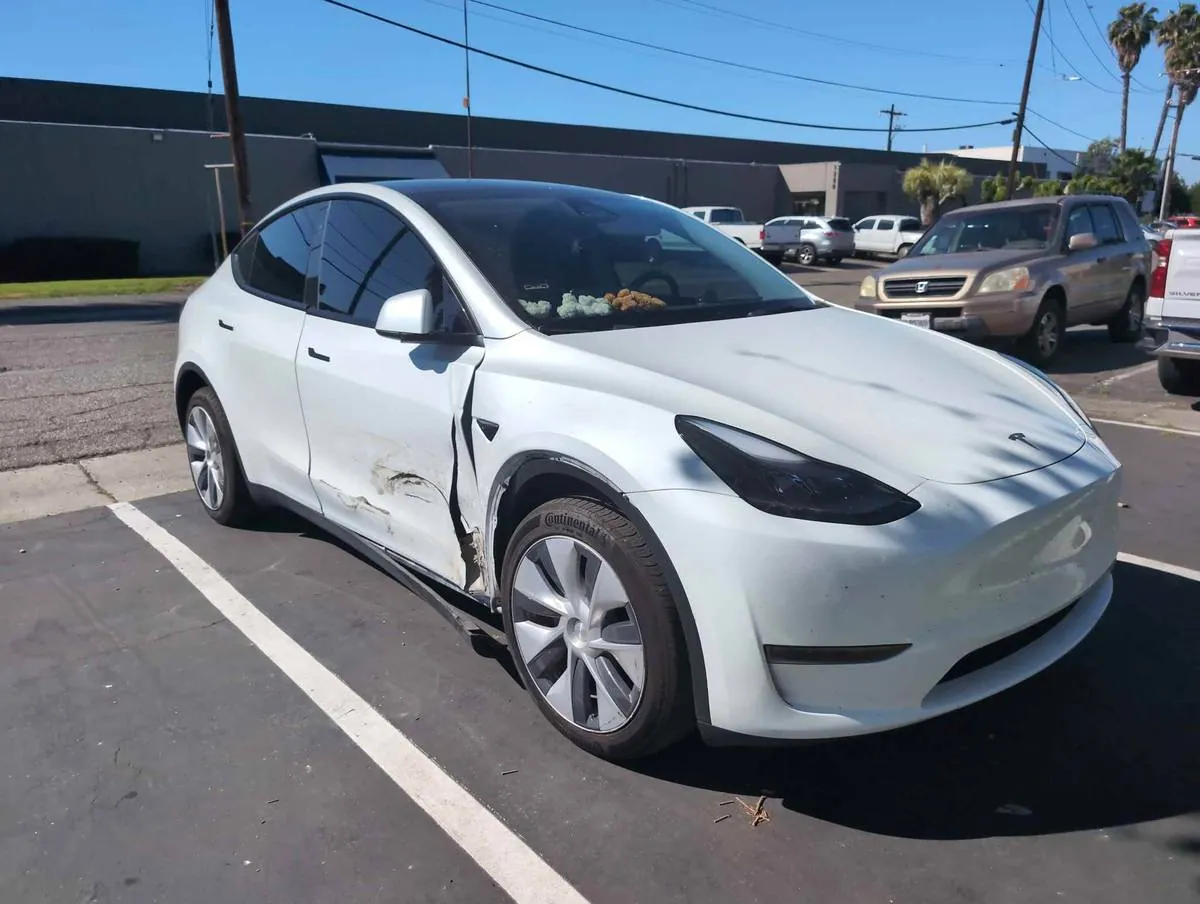 White Tesla Model Y with damaged front door and fender before collision repair in Irvine