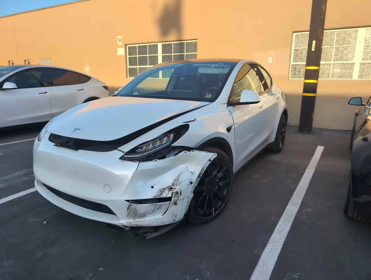 White Tesla Model Y with front bumper and headlight damage before repair in Irvine
