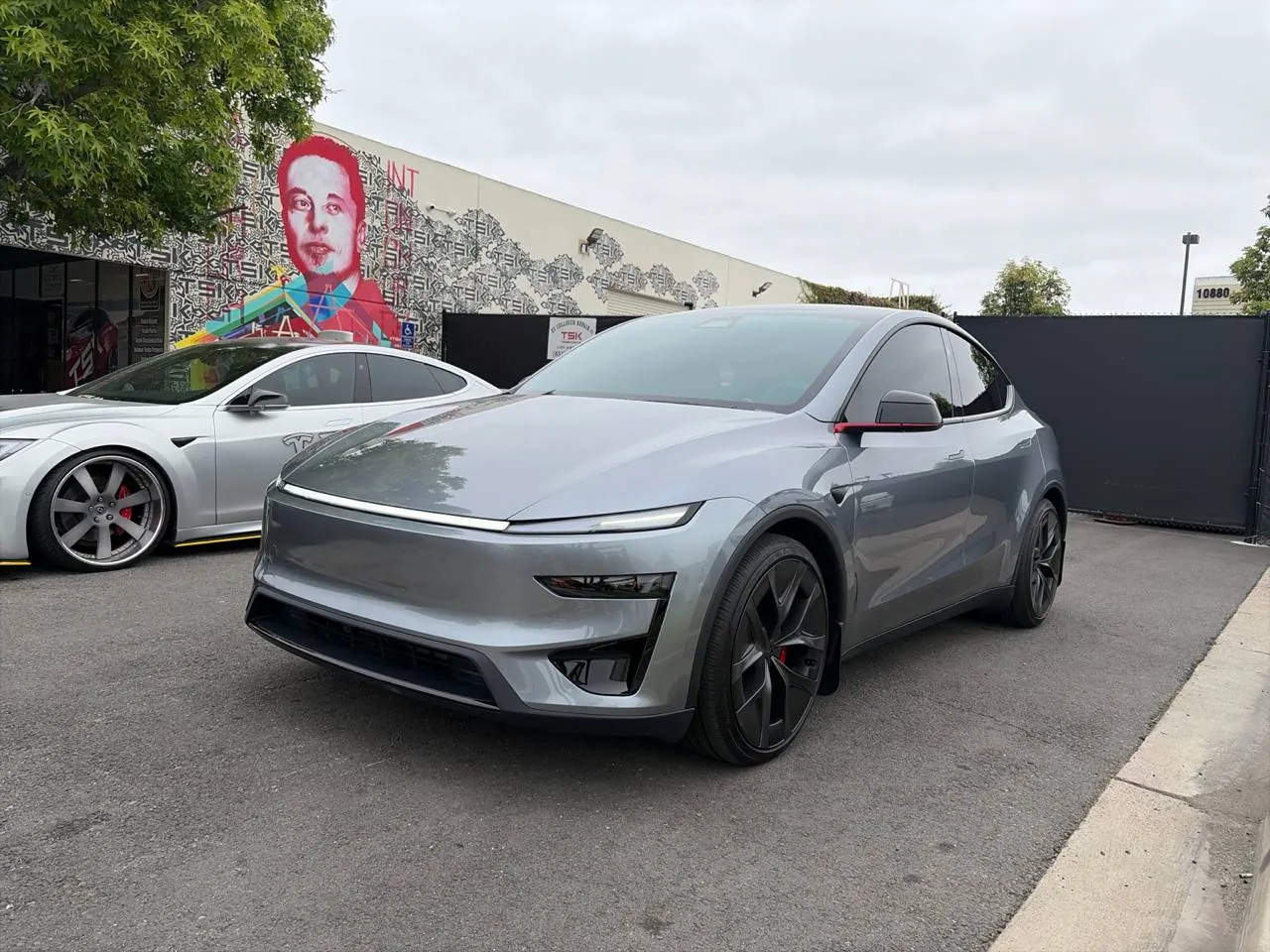 Refinished silver Tesla Model Y parked outside TSK EV collision repair shop in Irvine