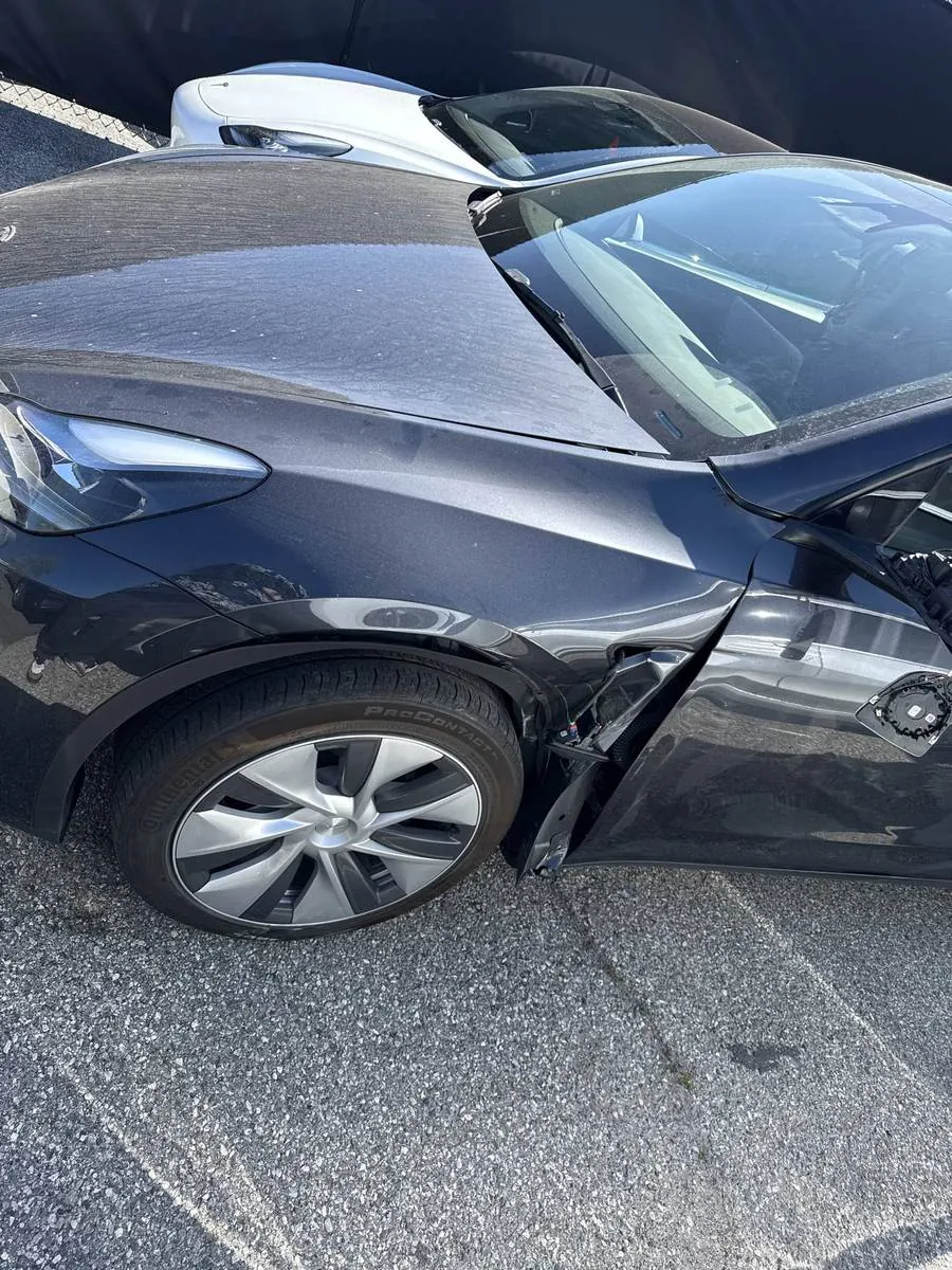 Damaged black Tesla Model Y front fender and door before collision repair in Irvine