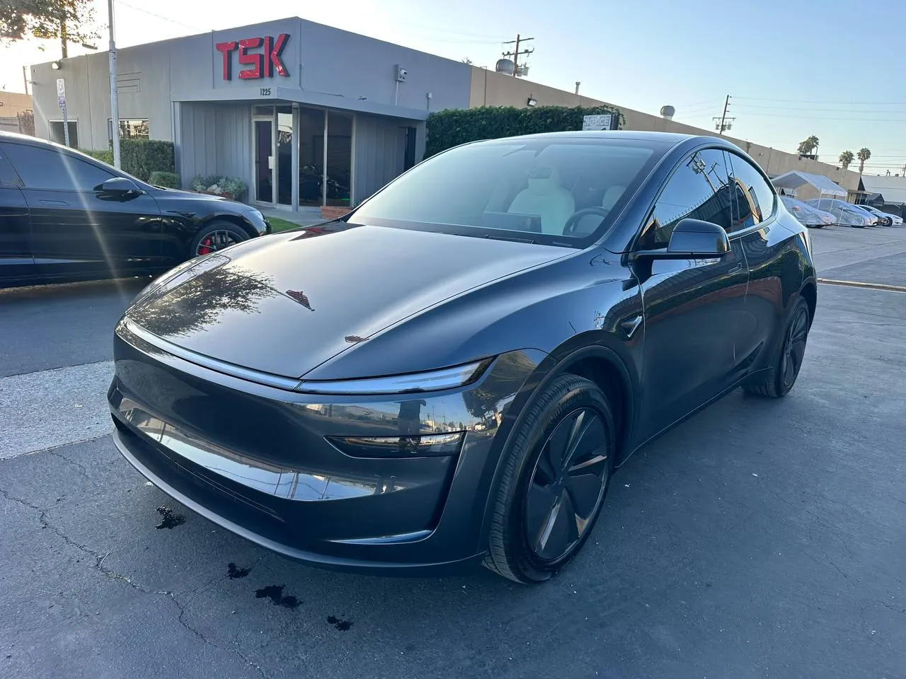 Gray Tesla Model Y parked outside TSK collision repair shop in Irvine.