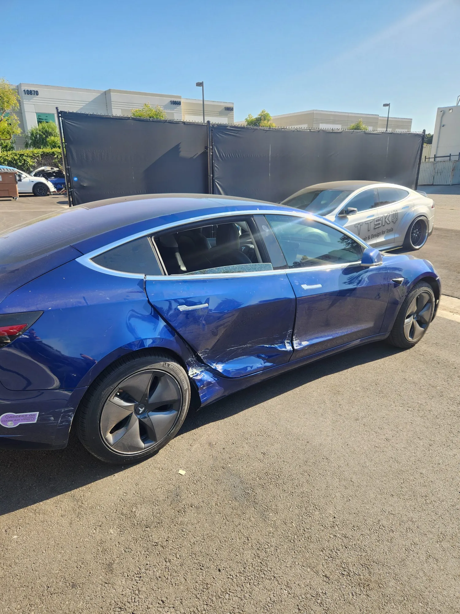 Blue Tesla Model 3 with crushed rear door and quarter panel damage before repair at TSK