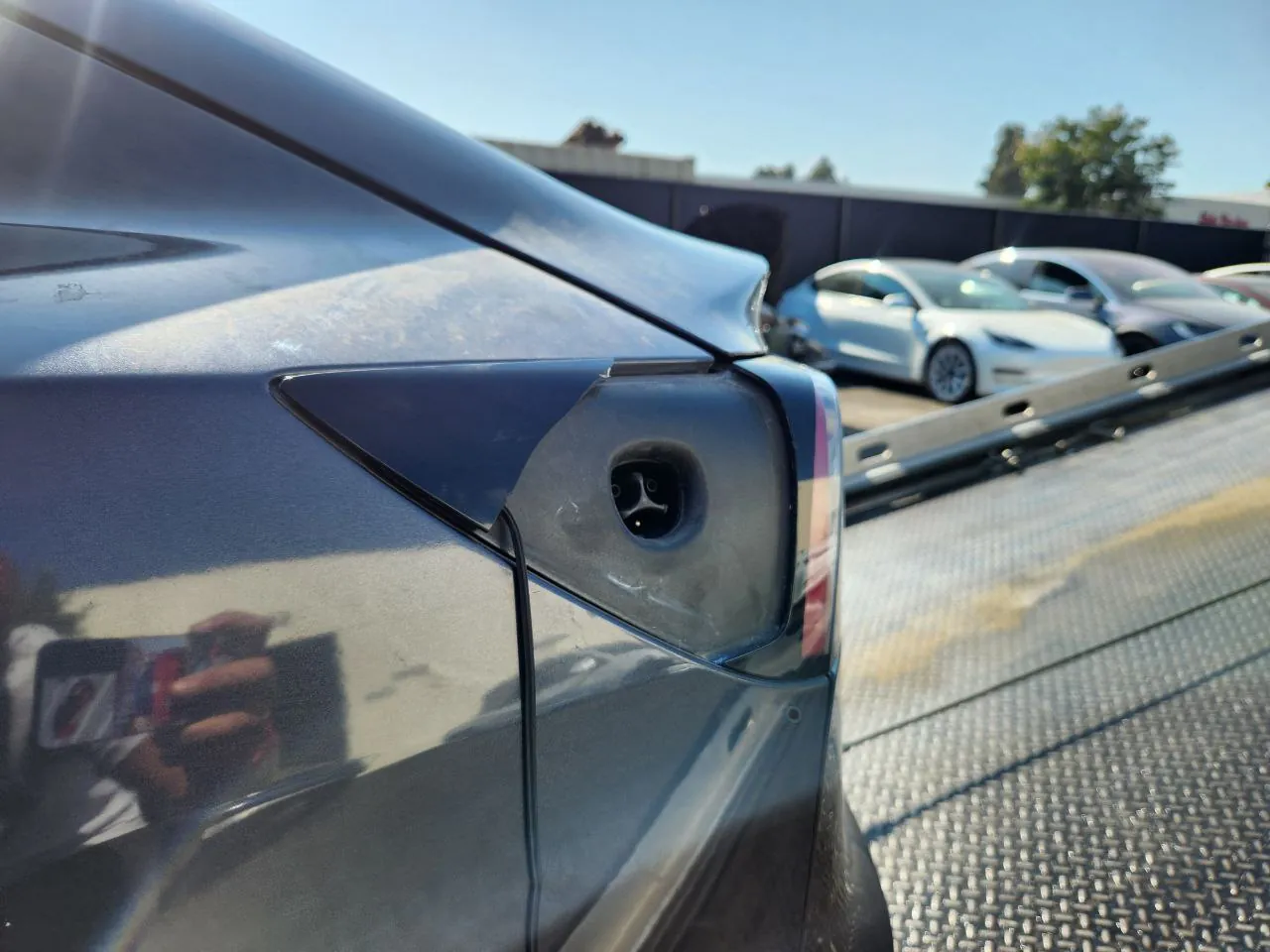 Tesla Model 3 rear charge port door open, showing charging inlet close-up